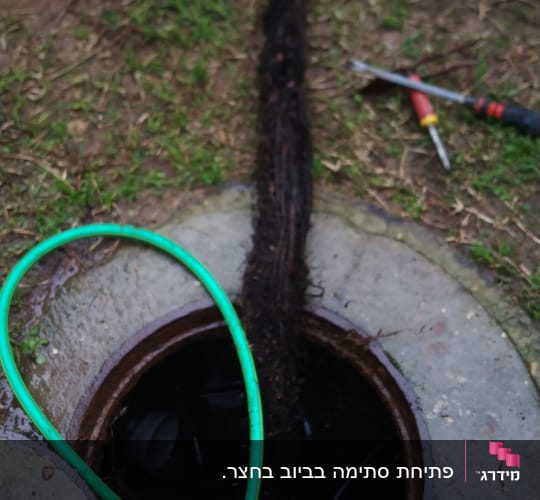 צינור ירוק וכלי עבודה ליד פתח ביוב